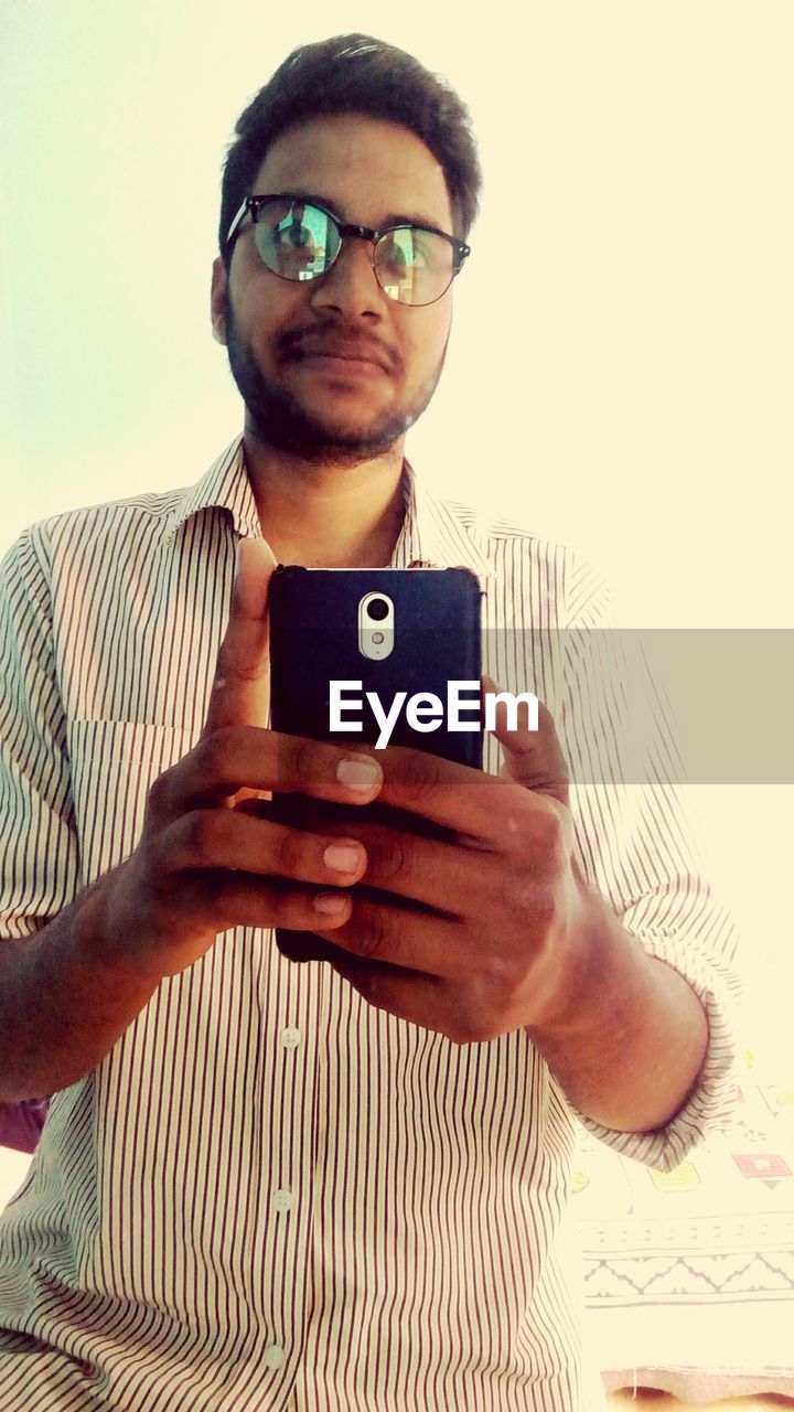 Low angle view of man holding smart phone against white background