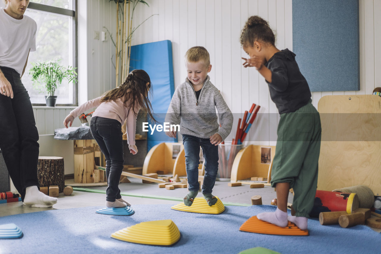 Happy male and female students playing in kindergarten