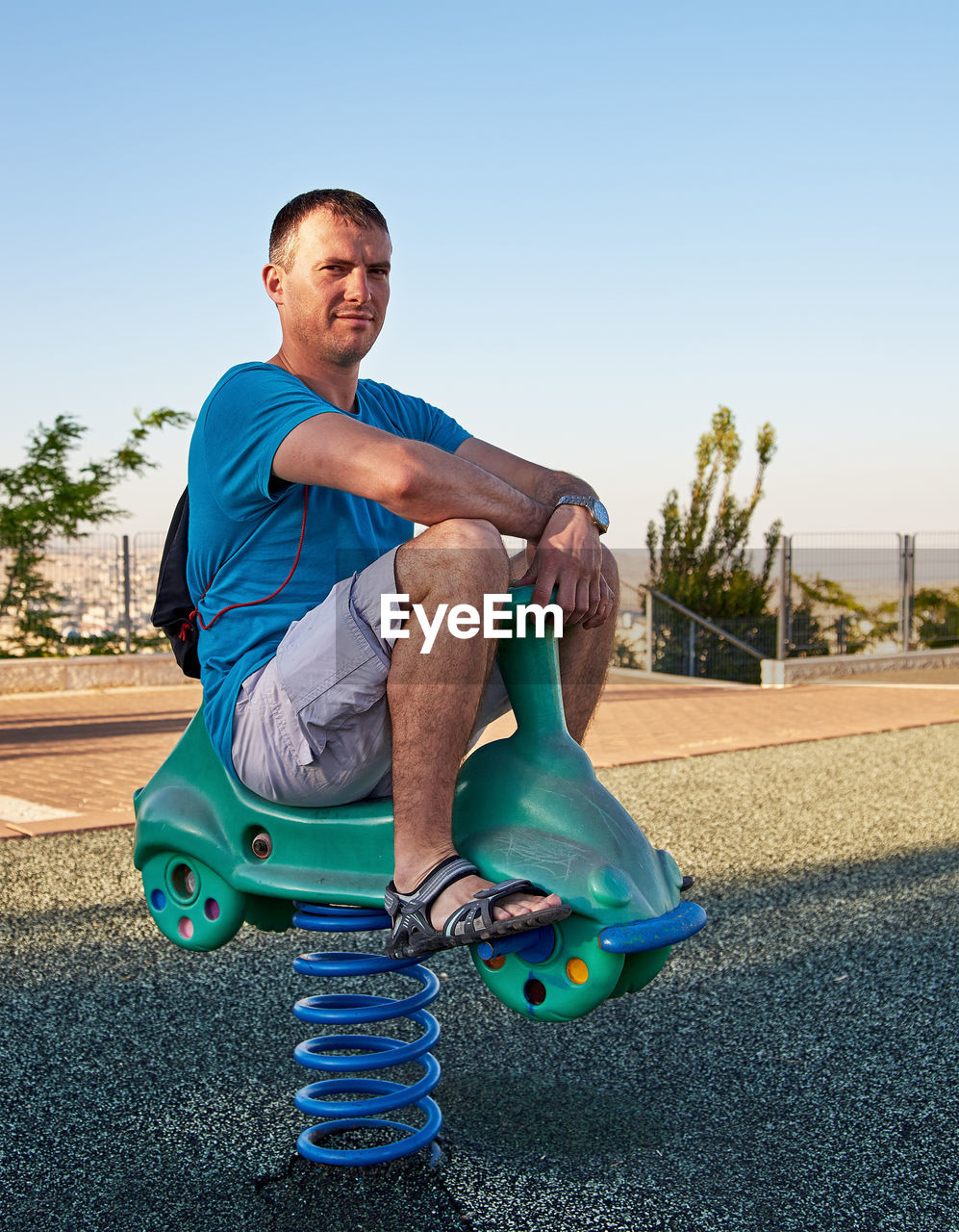 Portrait of man sitting on spring ride at playground