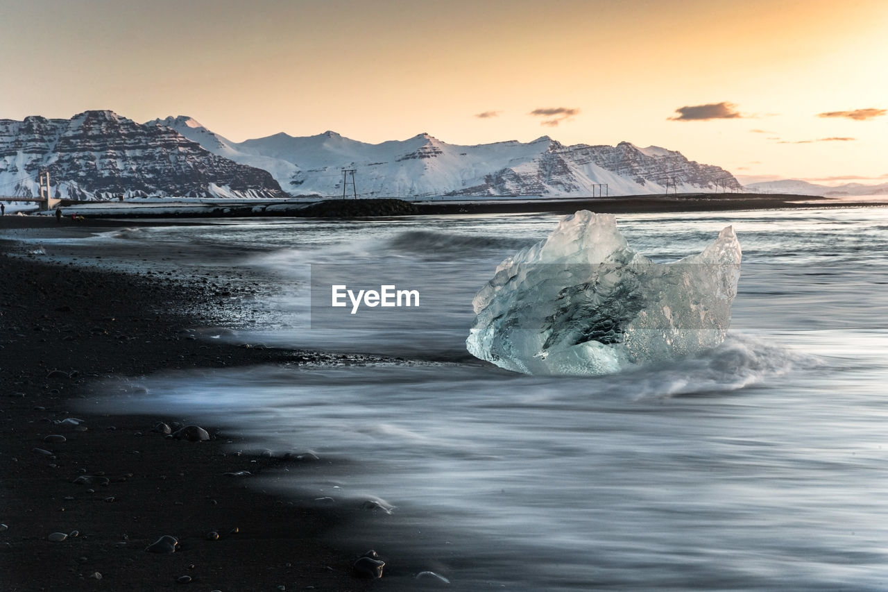 Scenic view of ice berg in sea against sky during sunset