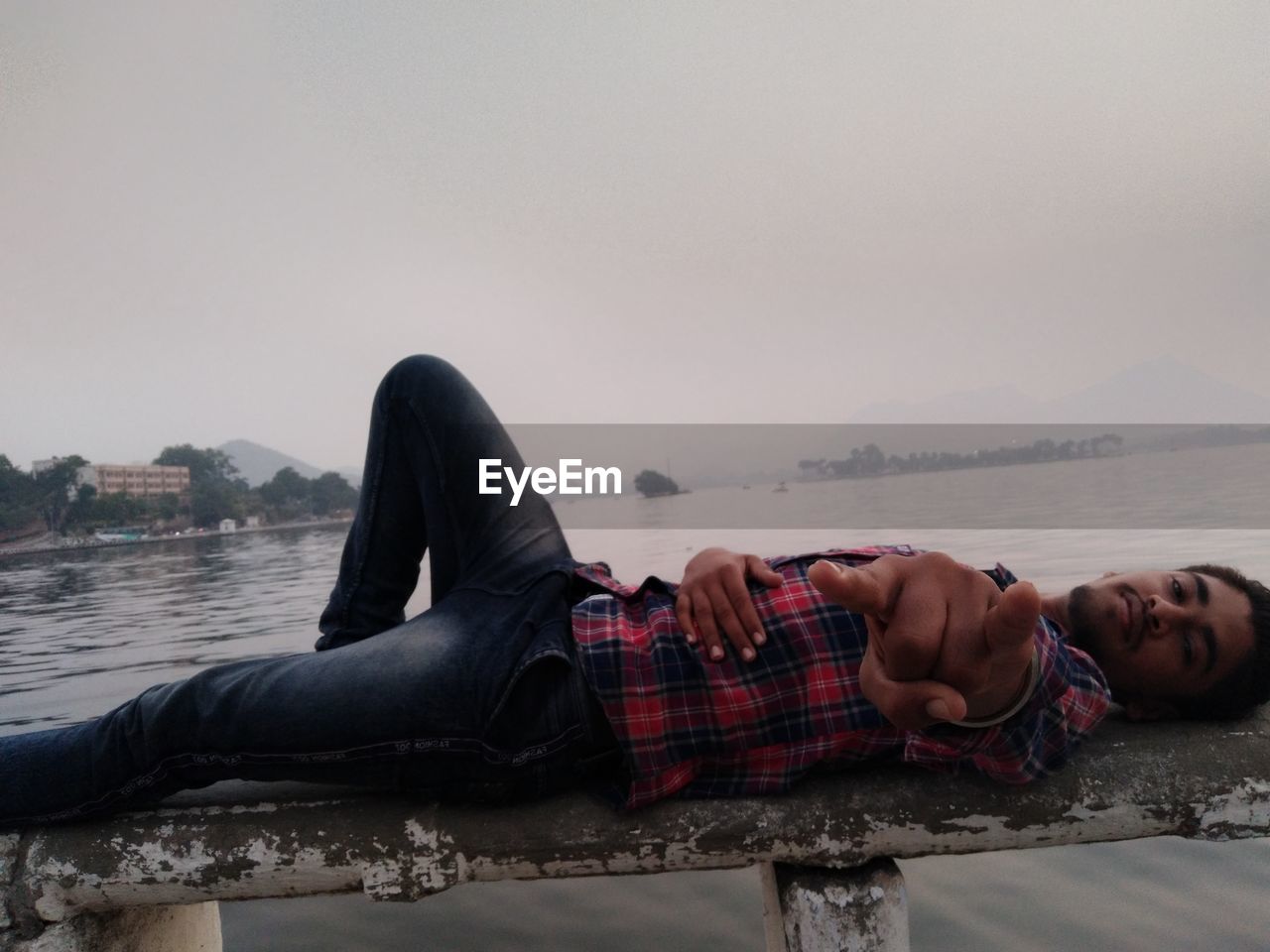 Portrait of young man lying down against sky