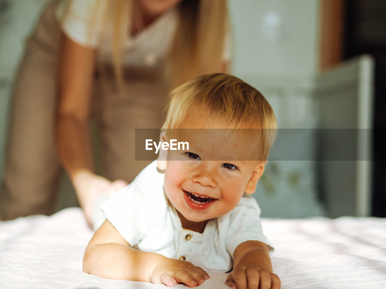 Young beautiful mother with long blond hair having fun with pretty baby boy at home