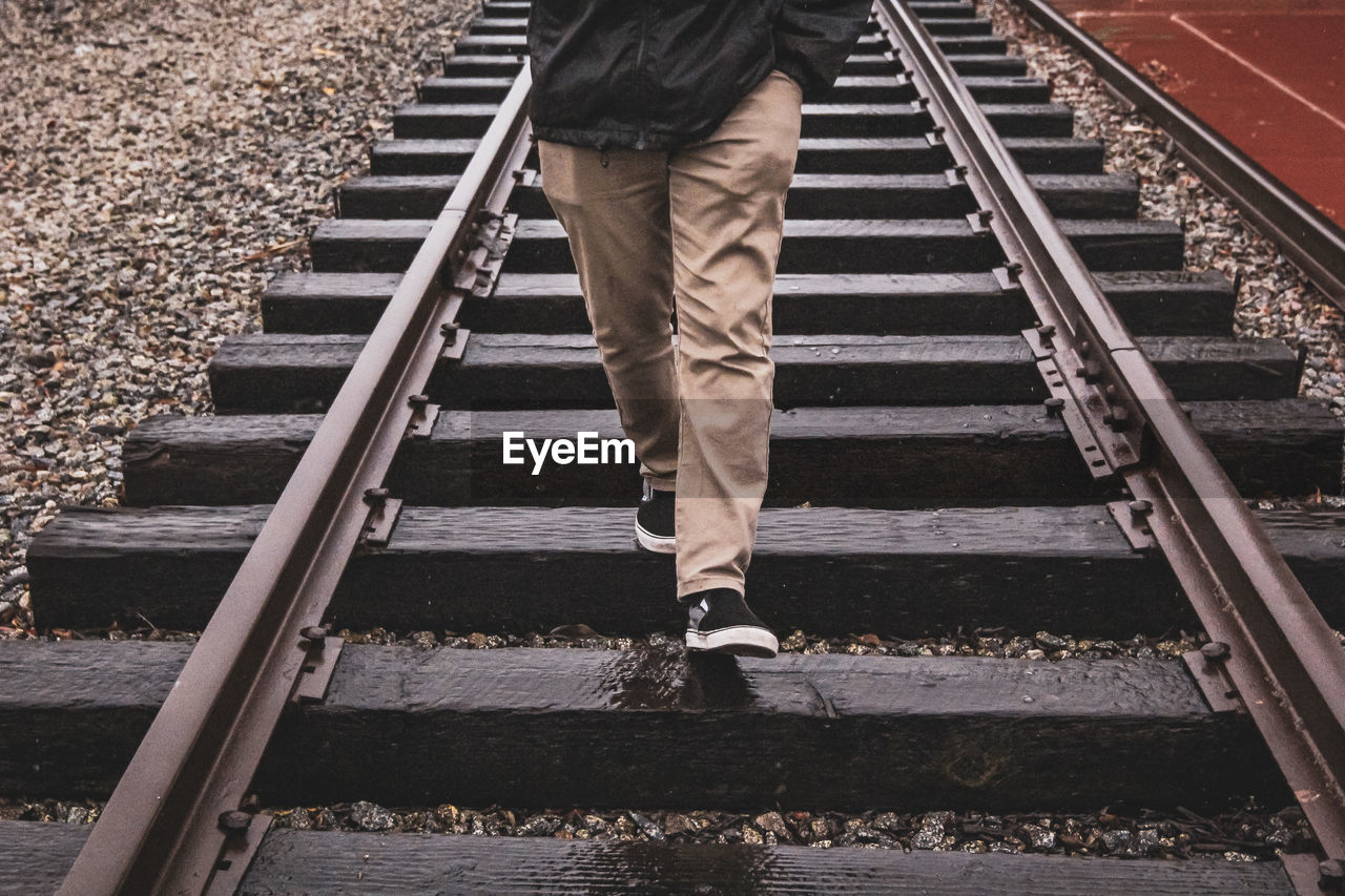 Low section of man walking on railroad track