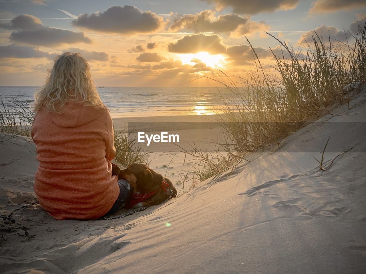 sand, sky, morning, land, sunlight, beach, one person, nature, water, sea, sitting, beauty in nature, rear view, cloud, vacation, holiday, trip, relaxation, women, tranquility, leisure activity, adult, scenics - nature, environment, ocean, wave, snow, solitude, clothing, full length, sun, landscape, child, shore, horizon over water, horizon, lifestyles, blond hair, outdoors, tranquil scene, hairstyle, childhood, sunrise, sand dune, long hair, female, winter, travel destinations, orange color, idyllic, travel, person, contemplation