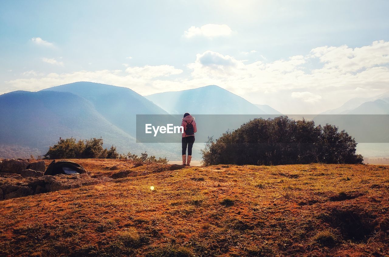 FULL LENGTH OF WOMAN STANDING ON MOUNTAIN AGAINST SKY