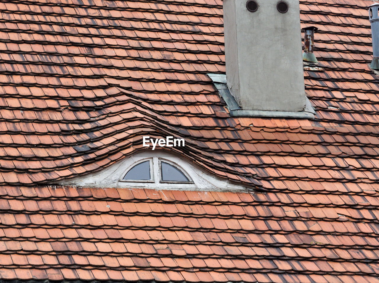 Red roof made of tiles with loftop window and chimney