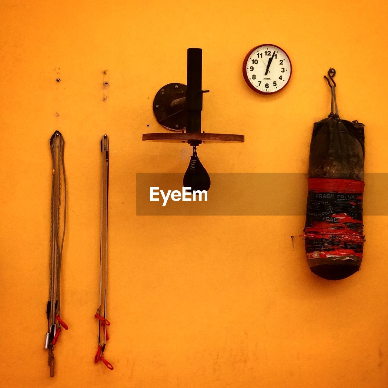 Wall clock with boxing equipment handing on orange wall