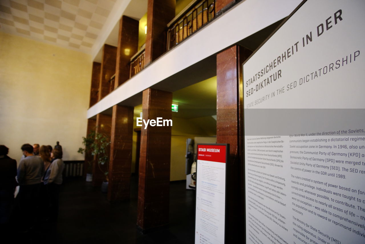 PEOPLE STANDING BY ILLUMINATED TEXT ON TABLE IN BUILDING