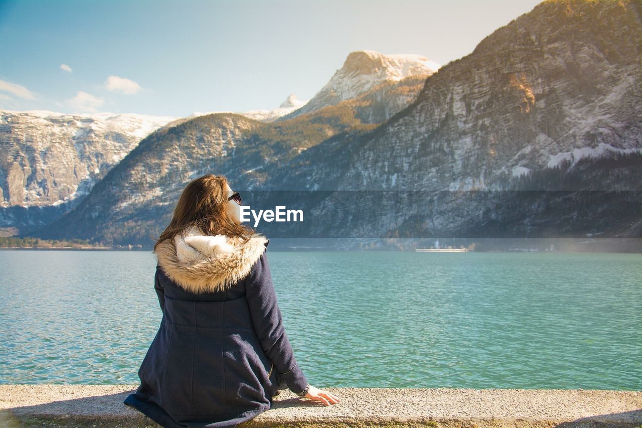 Rear view of woman looking at lake against mountain