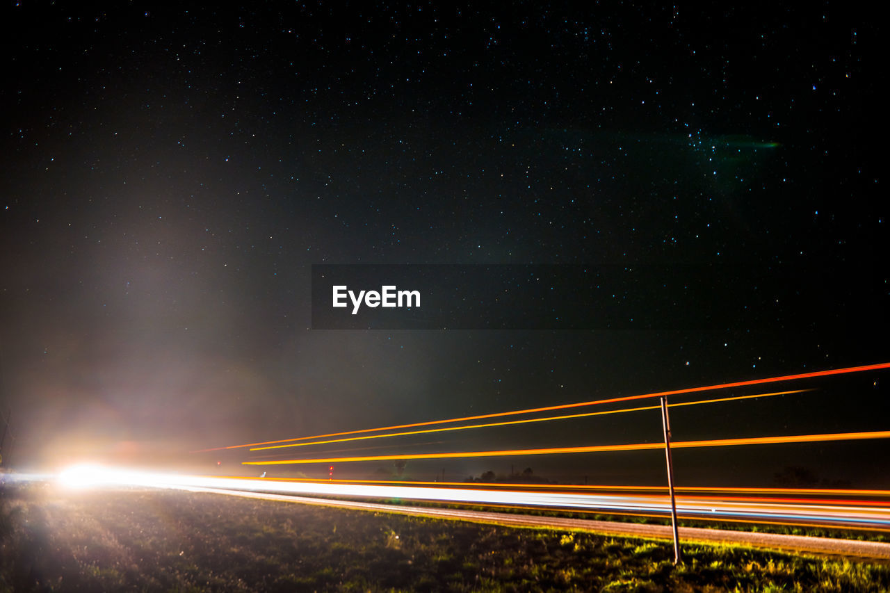 Illuminated field against sky at night