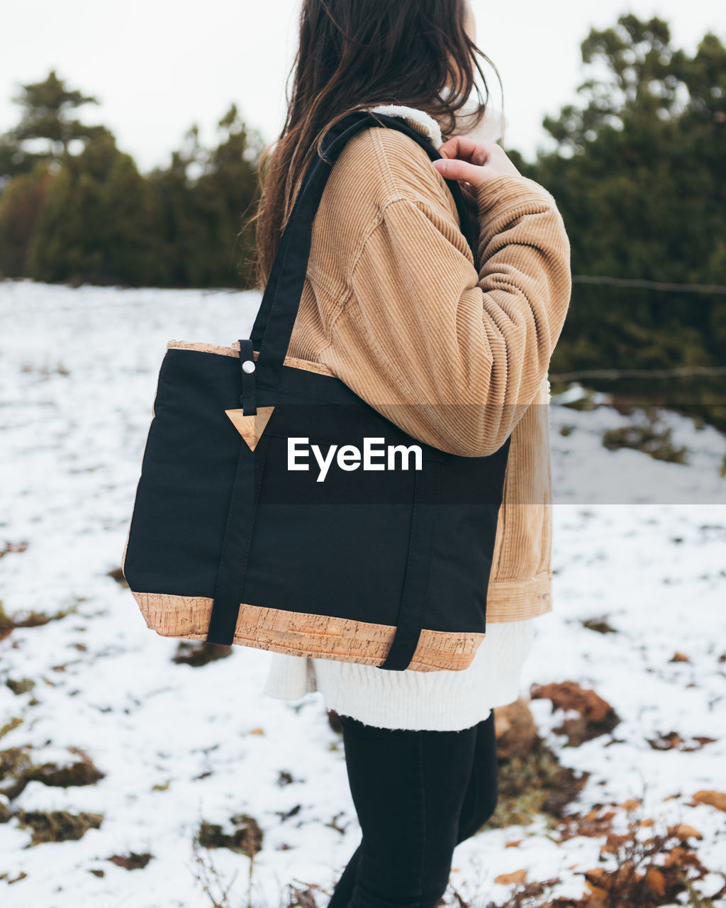 Young woman in trendy outfit walking in winter forest