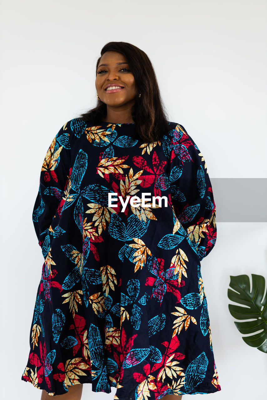 one person, portrait, adult, women, clothing, studio shot, smiling, indoors, white background, happiness, looking at camera, sleeve, pattern, fashion, floral pattern, emotion, young adult, front view, standing, female, hairstyle, spring, costume, dress, outerwear, traditional clothing, three quarter length, cheerful