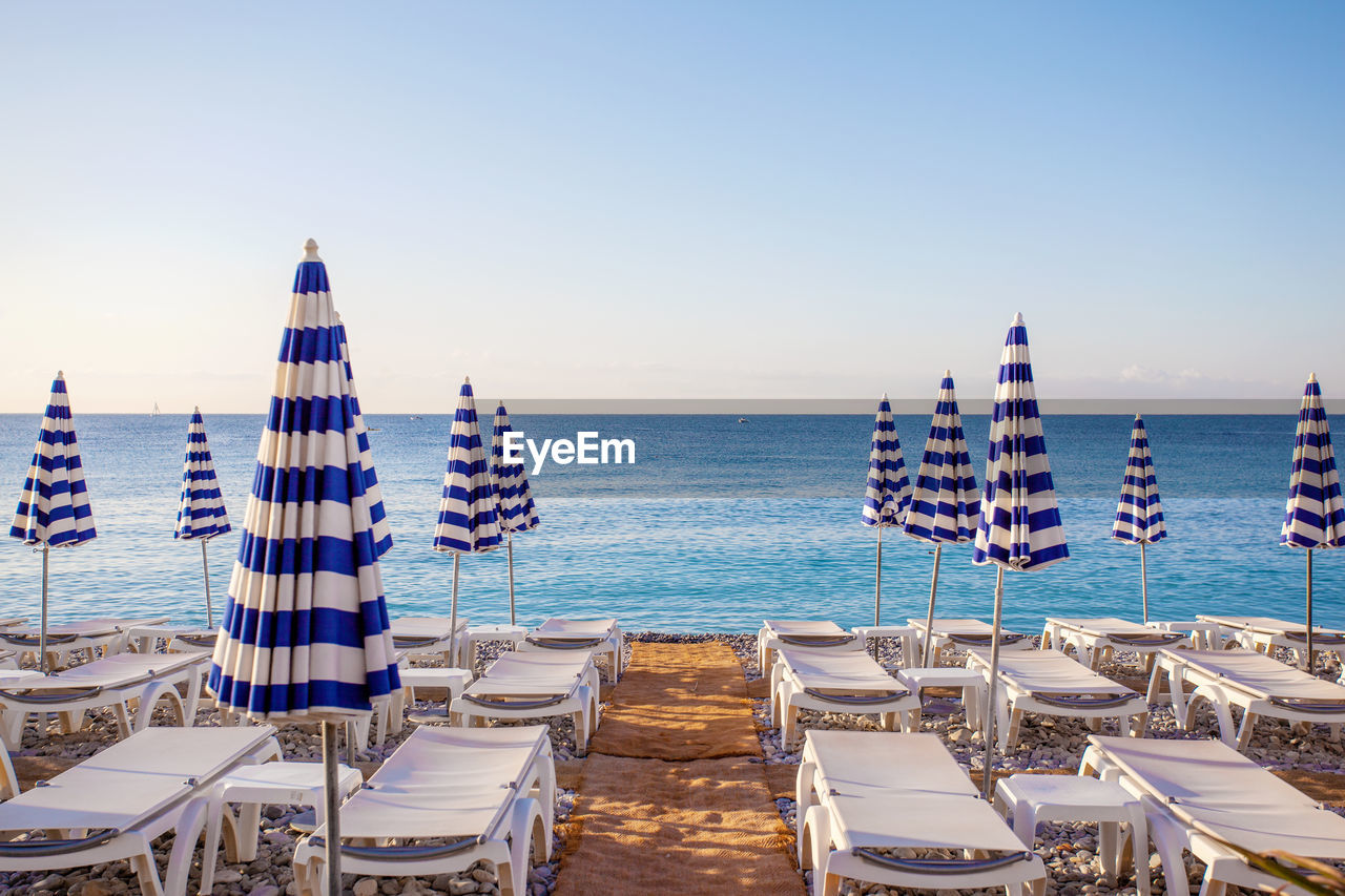 View of the blue striped umbrellas on the beach in nice, cote d'azur, southern france