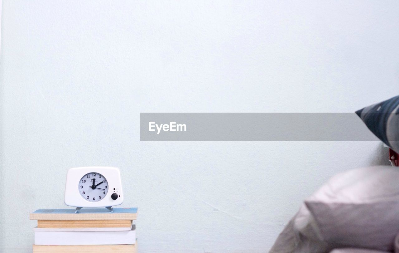 Alarm clock on stack of books at home