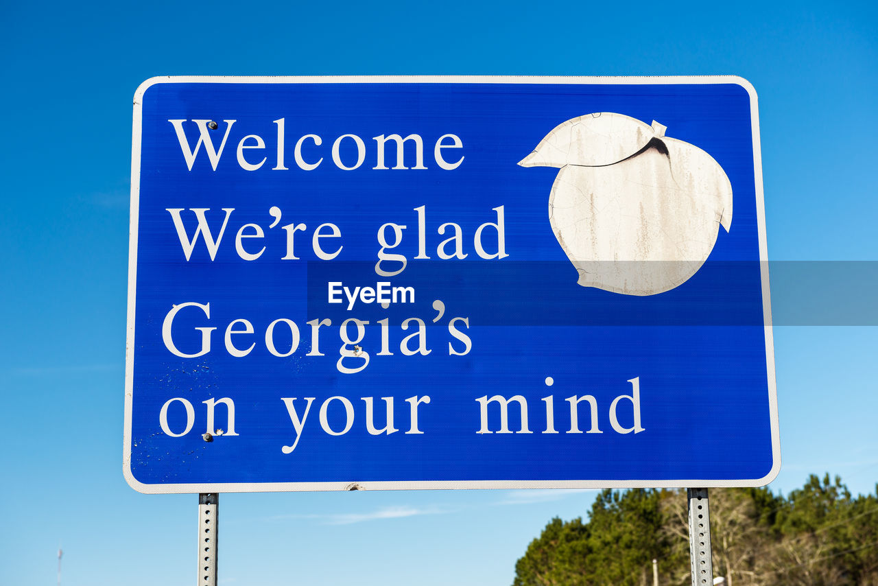 Low angle view of road sign against clear blue sky