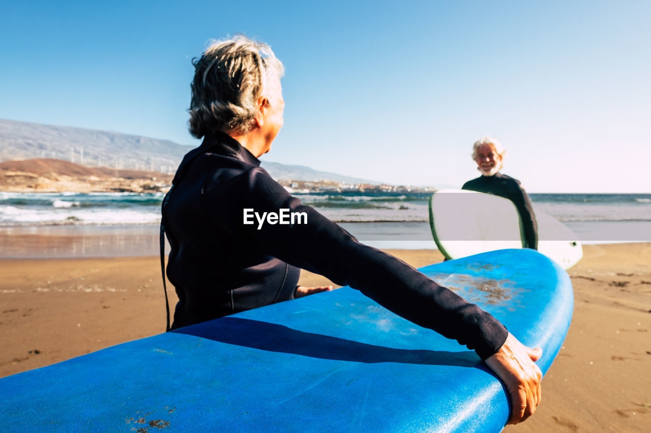 REAR VIEW OF WOMAN ON BEACH AGAINST SKY