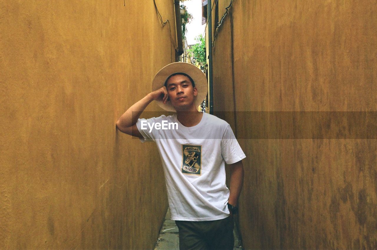 YOUNG MAN STANDING AGAINST WALL