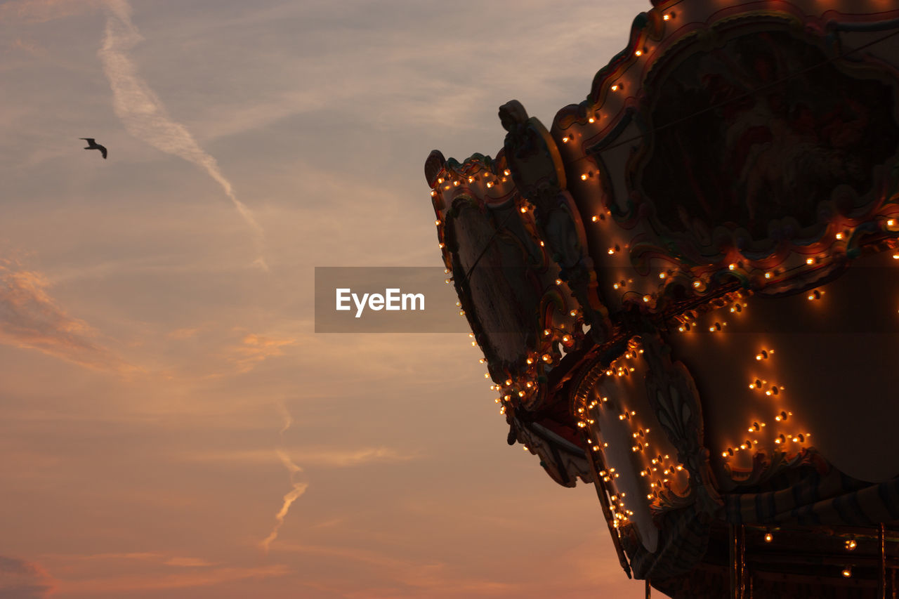 Low angle view of illuminated carousel against sky during sunset