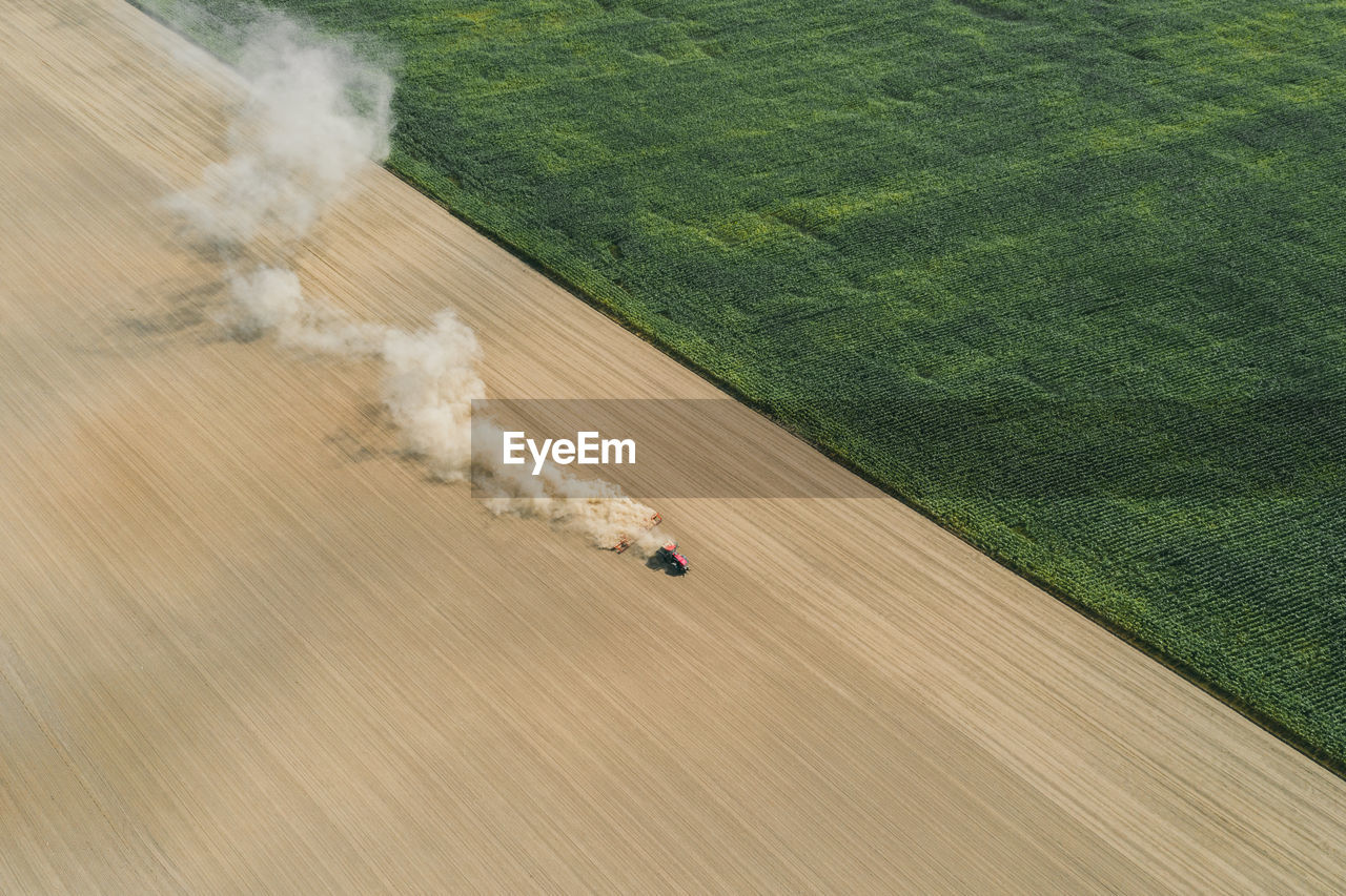 Aerial shot of farmer with a tractor on the agricultural field sowing. 