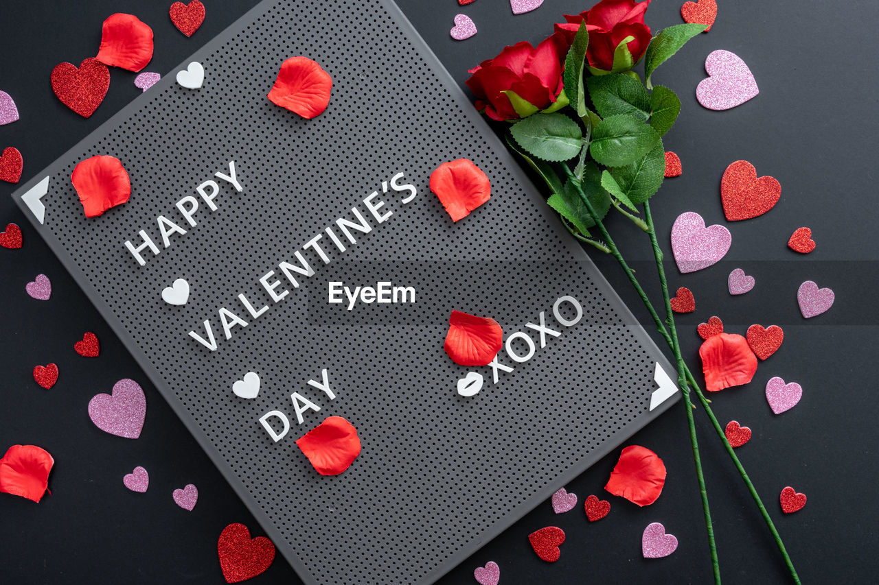 Beautiful valentine's day background with red hearts and roses on black banner background.