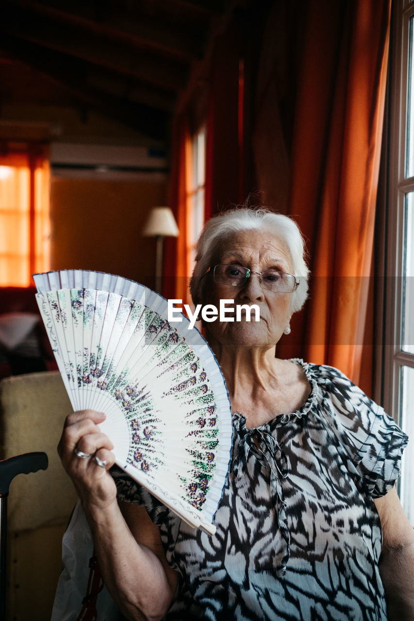 Portrait of old woman sitting holding a fan