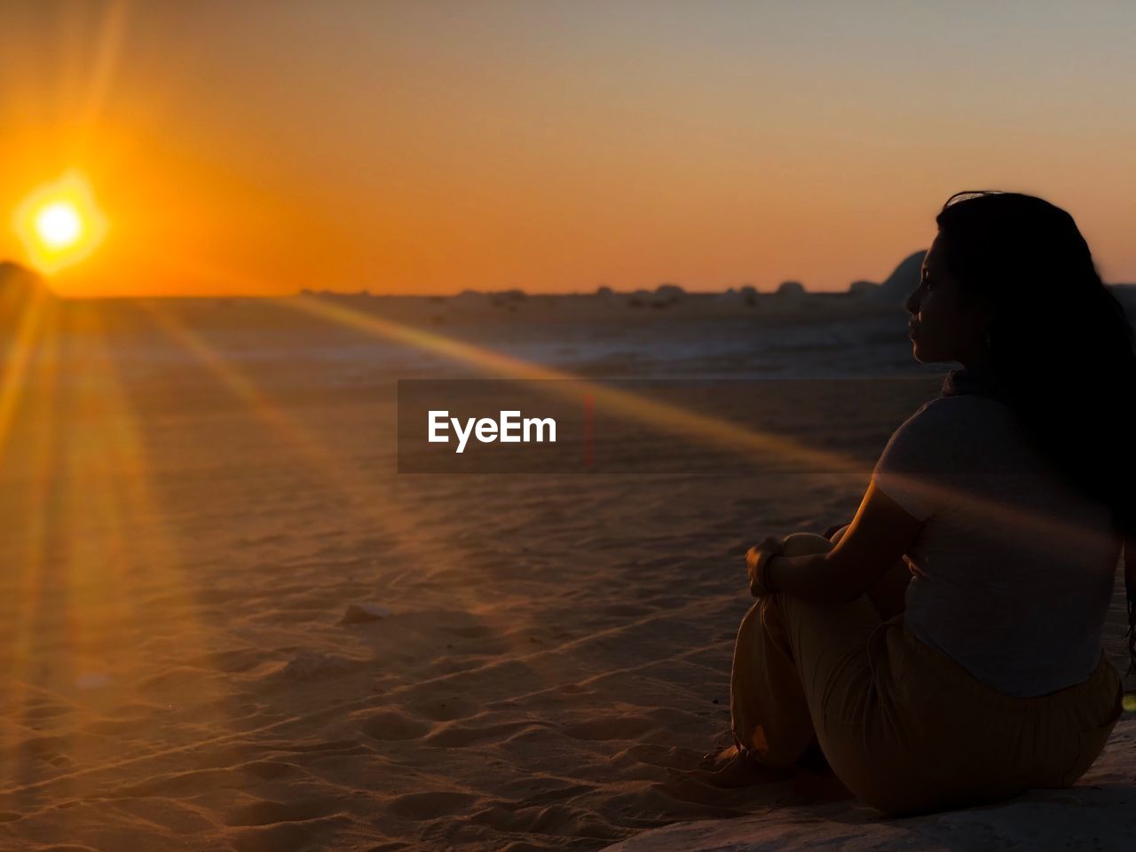 Woman sitting at beach during sunset