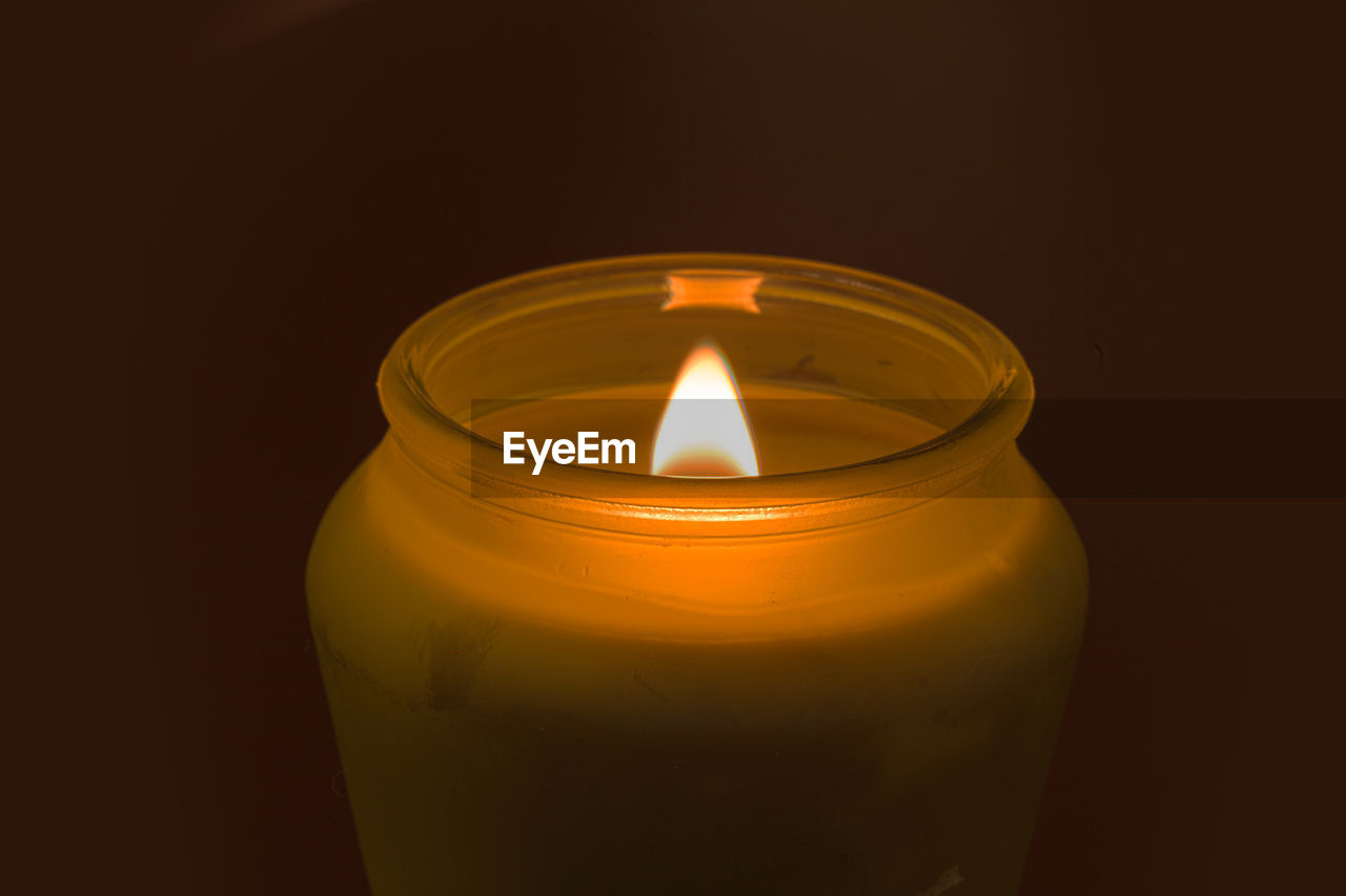 Close-up of lit tea light candle against black background