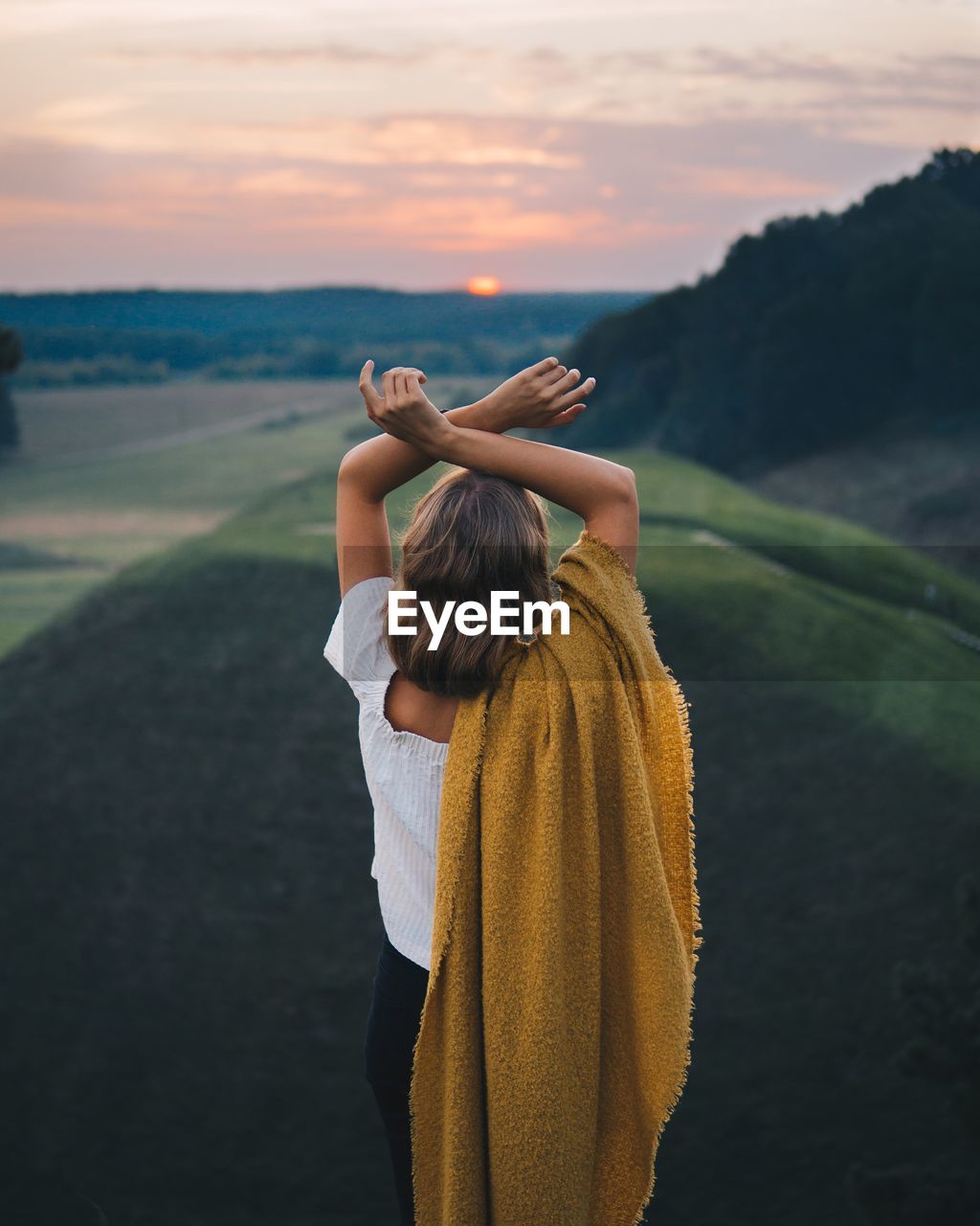 Rear view of woman standing outdoors during sunset