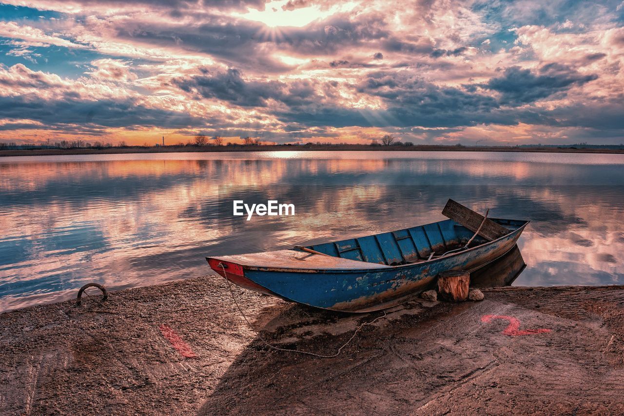 BOAT MOORED ON LAKE AT SUNSET