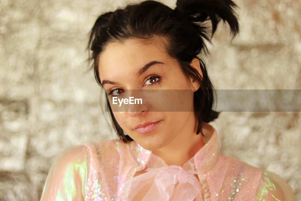 Close-up of young woman looking into the camera with glitter