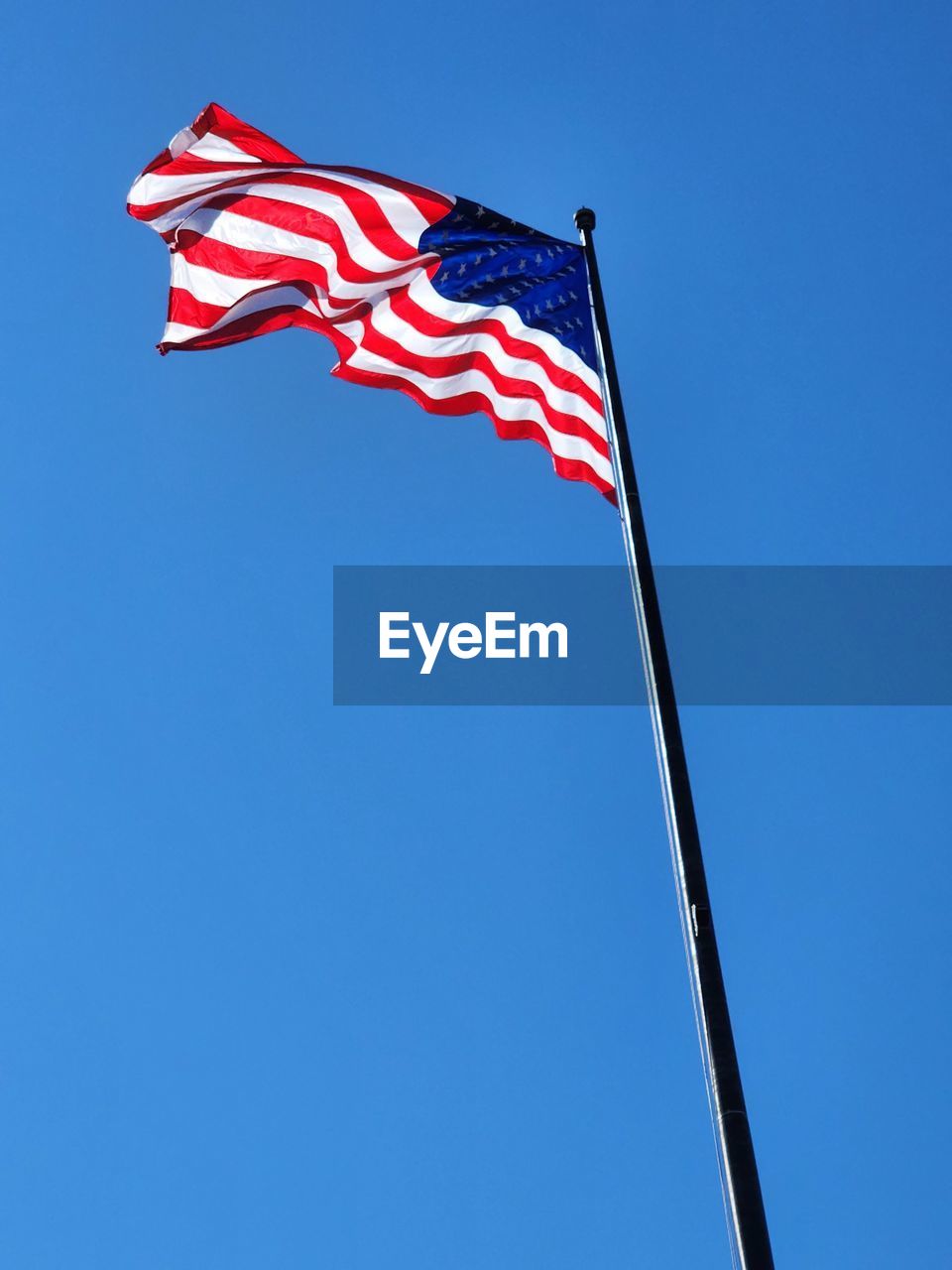 Low angle view of american flag against clear blue sky