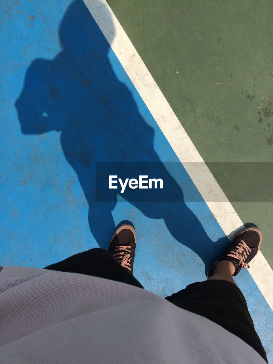 Low section view of man standing on tennis court