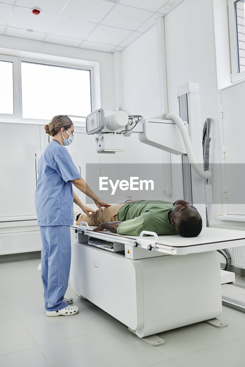 Nurse wearing scrubs taking x-ray shot of patient in clinic