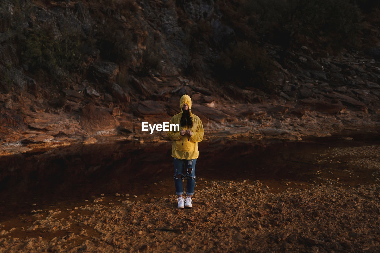 Young lady in yellow raincoat strolling in nature