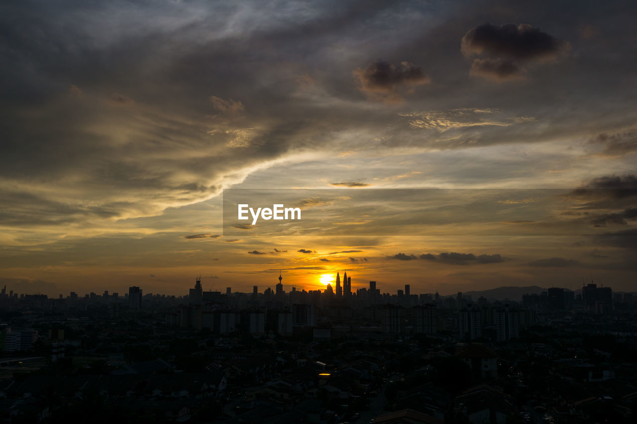 View of cityscape against cloudy sky during sunset