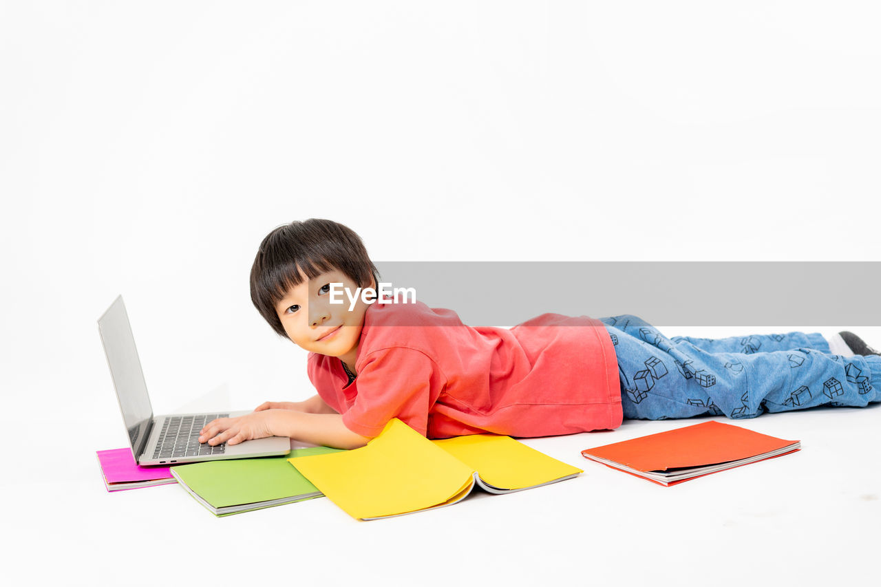 one person, computer, laptop, communication, sitting, indoors, technology, writing, wireless technology, using laptop, white background, adult, copy space, business, child, men, happiness, student, childhood, studio shot, person, casual clothing, smiling, relaxation, education, emotion, portrait, working, office, lifestyles, furniture, internet, activity