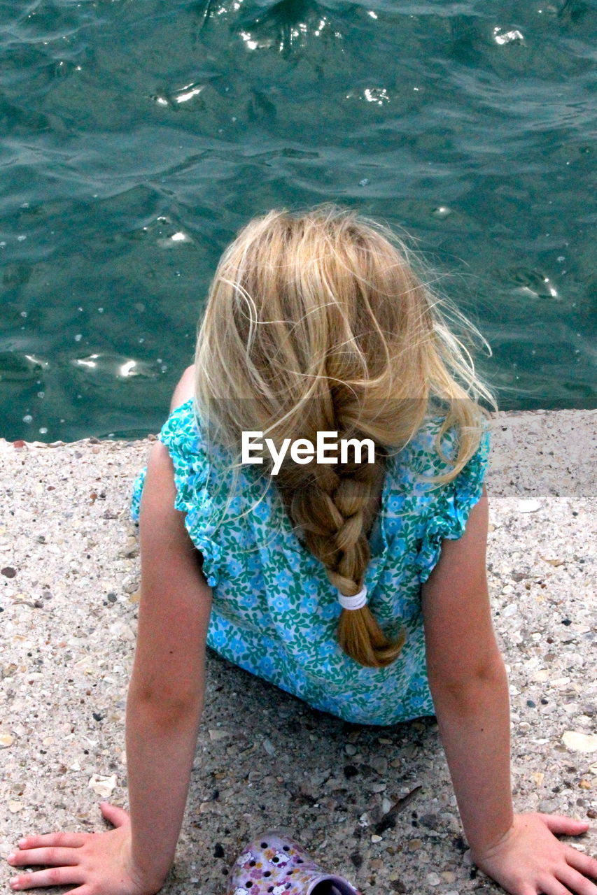 Rear view of girl sitting on pier against lake