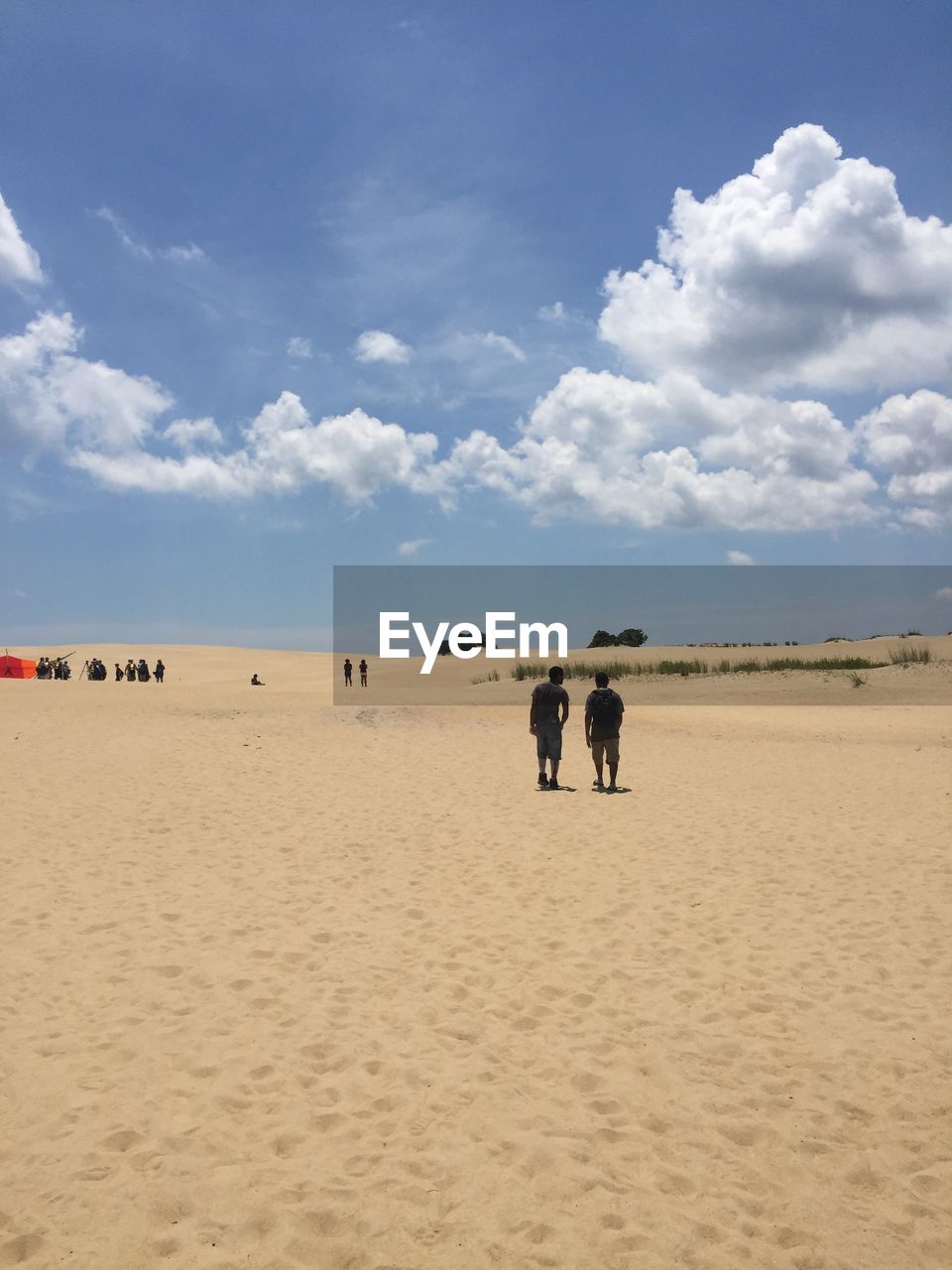 PEOPLE ON SAND DUNE AGAINST SKY