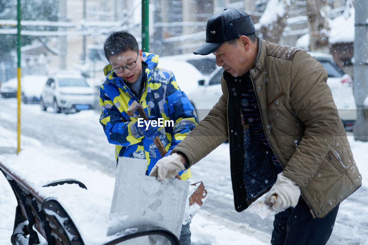 People making snowman on bench during winter