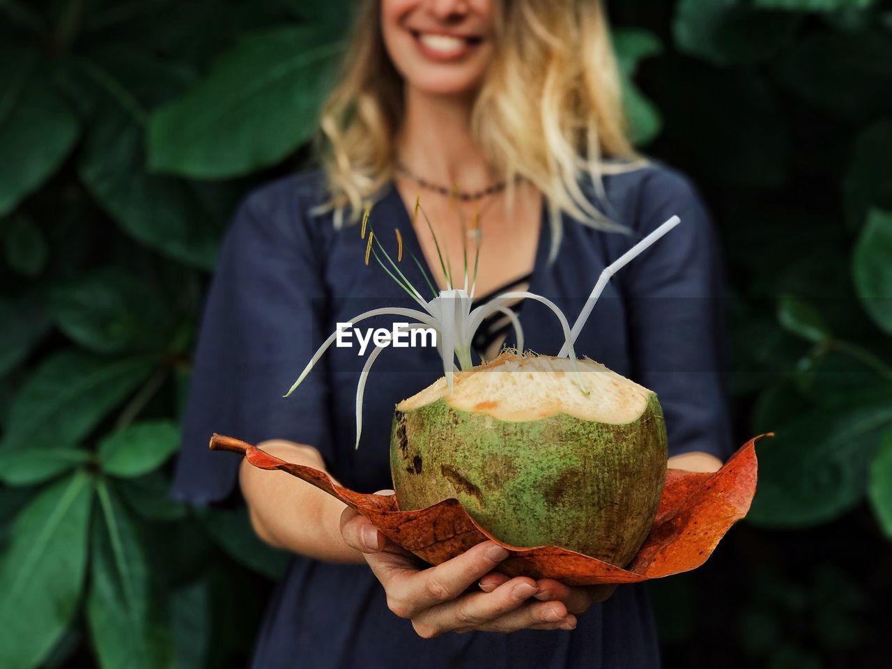 Midsection of smiling young woman holding coconut