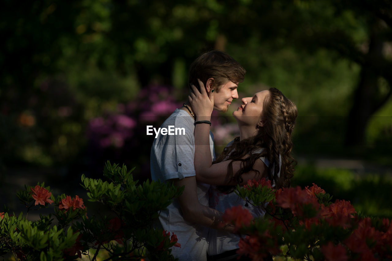 Side view of couple standing amidst flowers at park