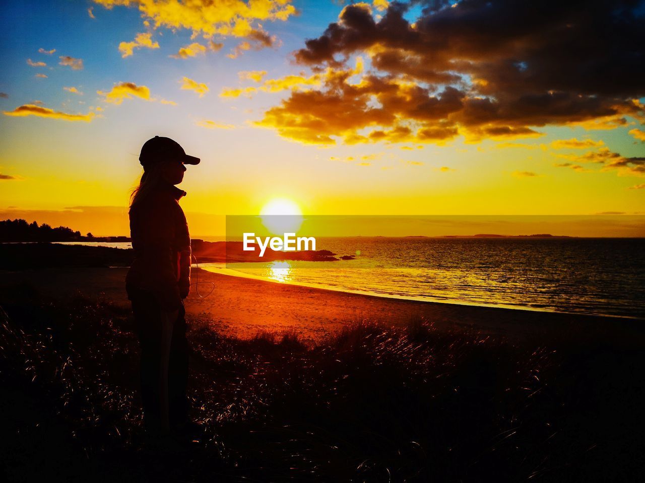 SILHOUETTE MAN STANDING AT BEACH DURING SUNSET