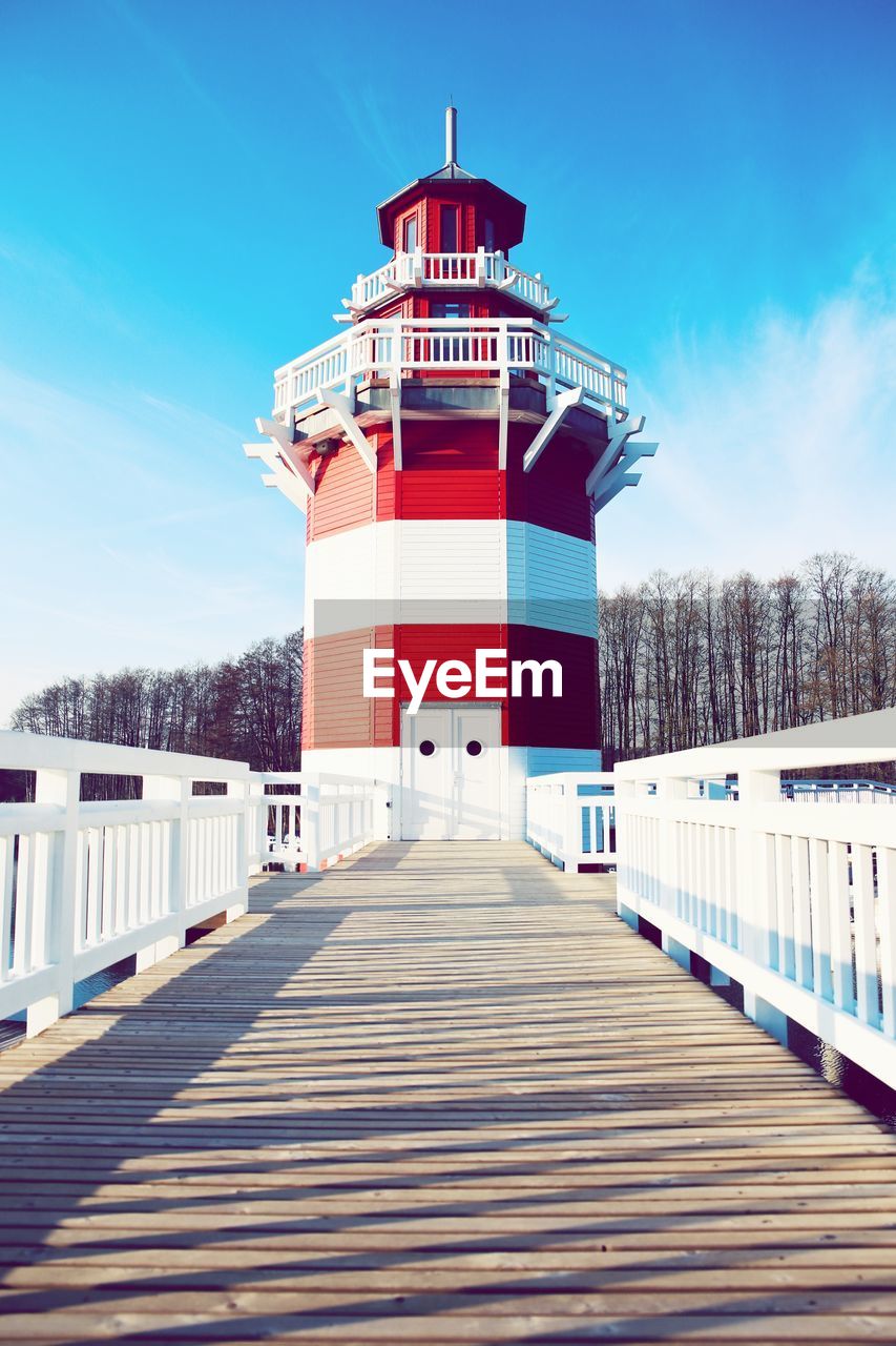 LIGHTHOUSE AMIDST BUILDINGS AGAINST SKY