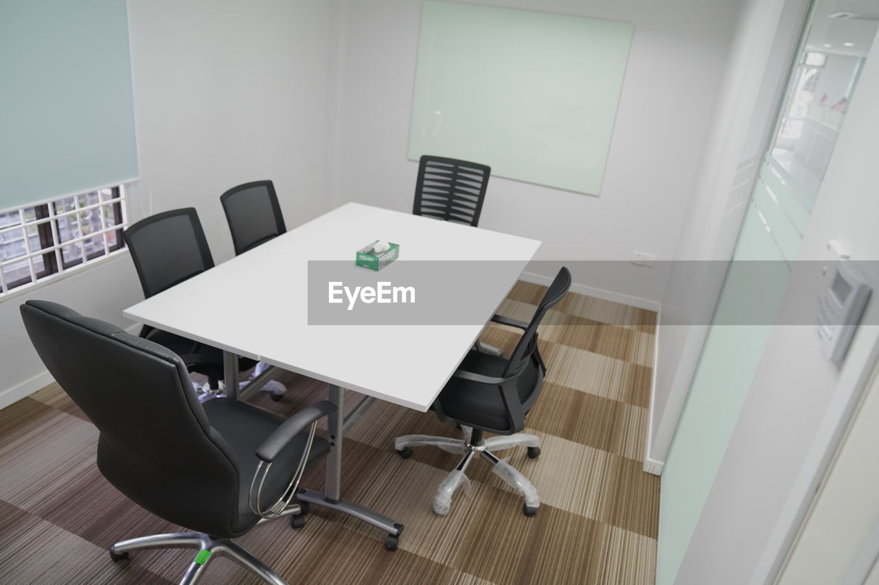 HIGH ANGLE VIEW OF EMPTY CHAIRS AND TABLES IN OFFICE