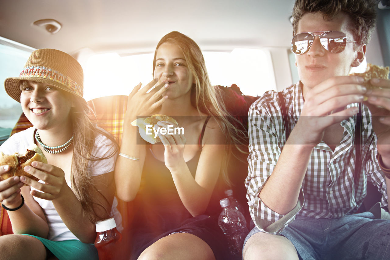 Three teenage friends having a snack in car