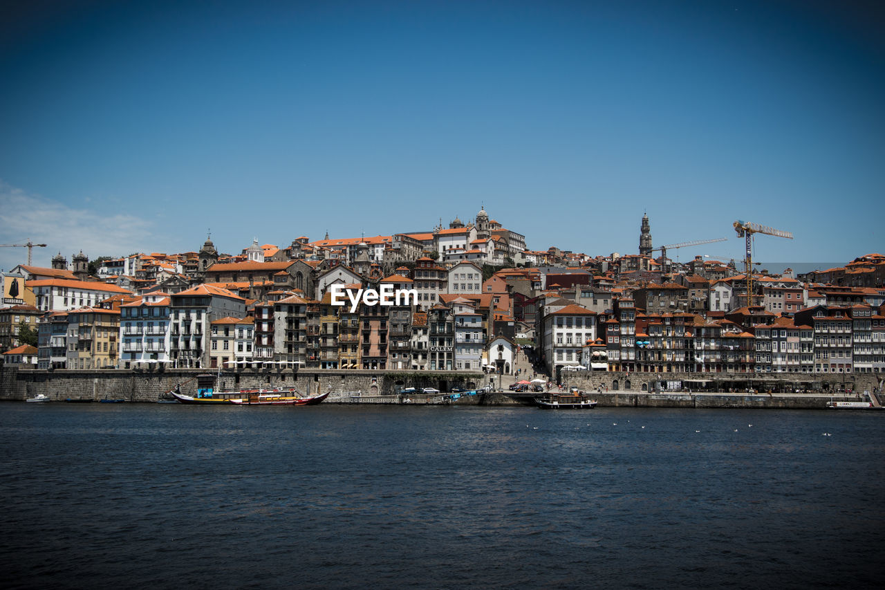 View of town by sea against clear blue sky