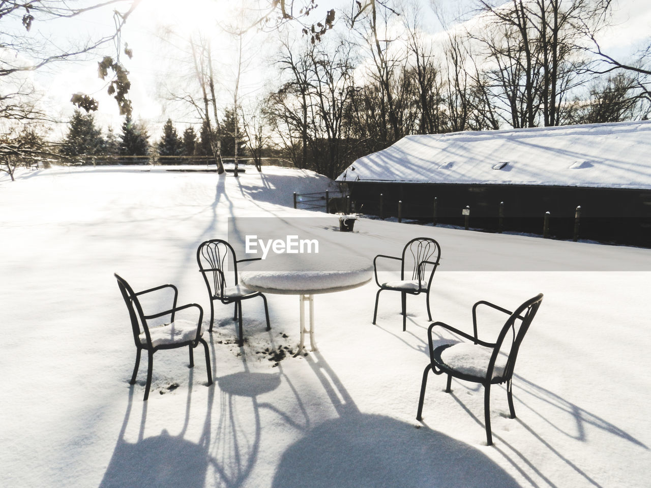 Empty chairs and tables on snow covered landscape
