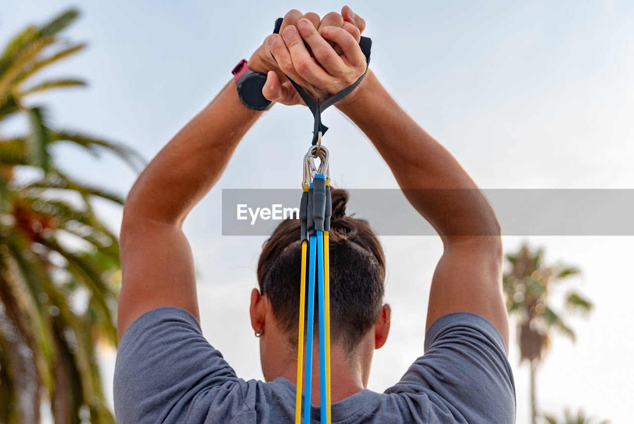 Low section of man holding rope against sky