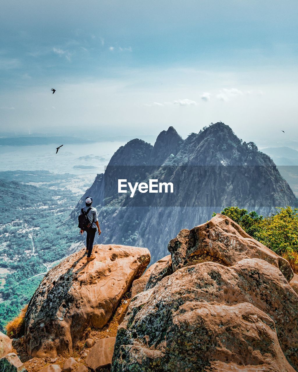 Rear view of man standing on rock against sky