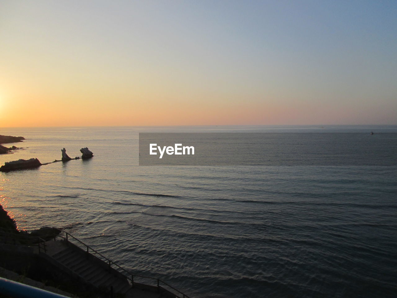 SCENIC VIEW OF SEASCAPE AGAINST CLEAR SKY DURING SUNSET